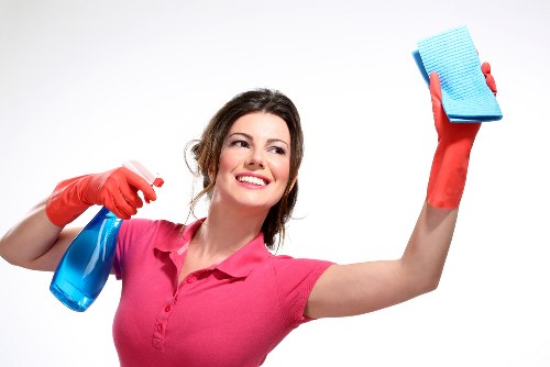 Professional cleaner sanitising desks and shared office areas in SE10